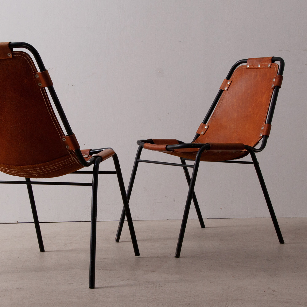 Les arcs Chair in Leather and Steel by Charlotte Perriand
France , 1967
フランスのスキーリゾート Les arcs（レ・ザルク）の為、1967年に Charlotte Perriand（シャルロット・ペリアン）によってセレクトされたレザーチェア。イタリアの家具メーカーにて製作されたと言われるこちらのチェアは一般に向け販売されることは無く、レ・ザルク　スキーリゾートのみで使われていました。
ペリアンはレ・ザルクの開発計画に参画、施設の設計や内装などトータルにプロデュースしました。
スチールパイプを曲げた簡素なフレームにホワイトステッチが施された頑丈なレザーシートをリベットで固定。腰掛けるとレザーシートがフレームに吊り下がるシンプルでありながら特徴あるデザイン・構造、軽量でスタッキング可能な機能性と利便性が魅力的な一脚です。
