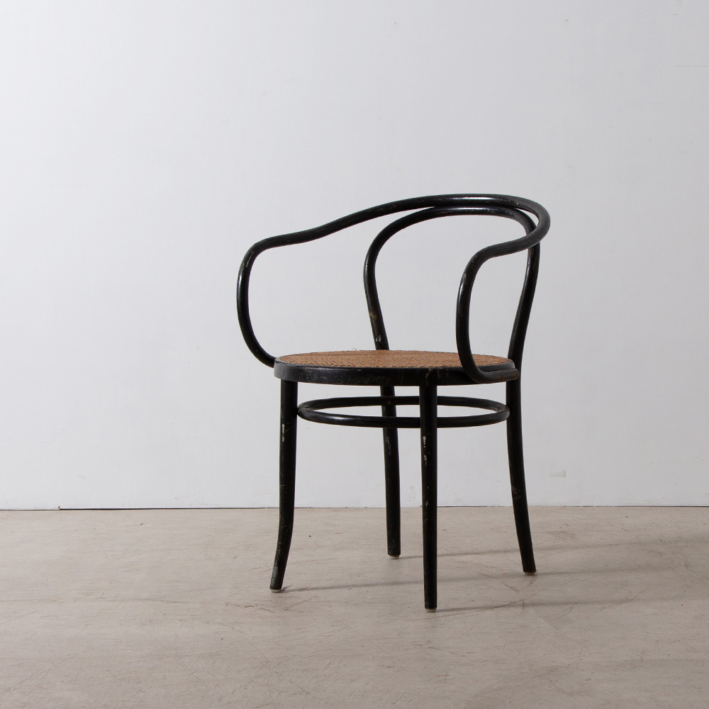 B9 / 209 Arm Chair for THONET in Wood , Rattan and Black
Austria , 1920s - 30s
THONET（トーネット）社より、ヴィンテージの209アームチェア。
別名「コルビュジエ・チェア」としても良く知られるこの椅子は、建築家のル・コルビュジエが愛用し、1925年にパリで開催された「現代装飾・産業美術国際博覧会」のエスプリ・ヌーヴォー館、1927年ヴァイセンホーフ・ジードルンク住宅などで採用されています。
事務用の椅子として開発された B9（後のNo209）はエレガントでクラッシックな佇まいが魅力の曲げ木椅子の名作です。デスクチェア、ダイニングやベットルームなどのプライベートなスペースなど場所を選ばずご使用頂けます。 
1920年代に　MUNDUS社 と THONET社 が合併した頃に製造されたモデルになり、長い年月を経て経年変化した美しいフレームやラタンの風合いは美しく、ヨーロッパ全土でも滅多に出回らないピースです。
全体的に経年の小傷やスレはありますが、日常使いいただけるヴィンテージコンディションとなっています。
