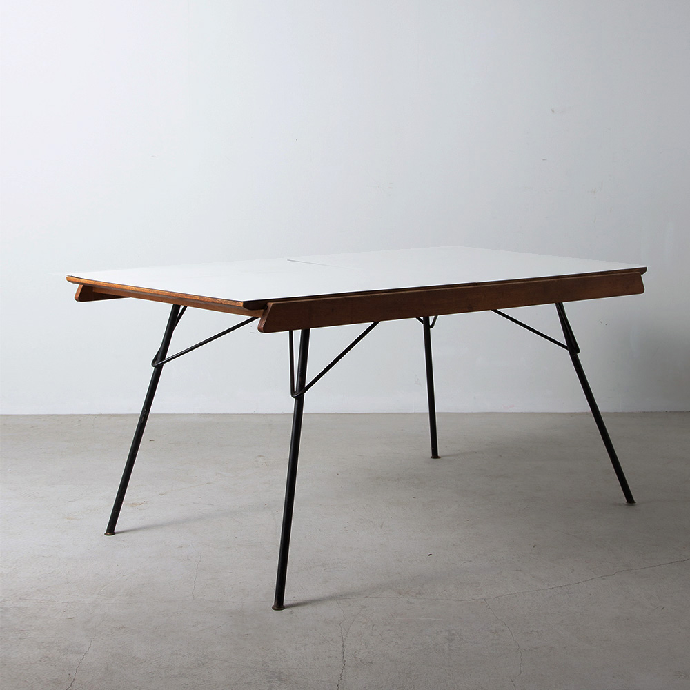 Extention Dining Table Model “Ermenonville” by Gérard Guermonprez for Magnani in Oak , Iron and Wihte
France , 1957
フランス人デザイナー Gérard Guermonprez（ガーモンプレ）によって Magnani社 のためにデザインされたモデル Ermenonville ダイニングテーブル。
1957年にデザインされたこの希少なモデルは、中央部分はエクステンションが可能で、両翼の天板を動かし中央に隠された拡張天板を回転することで、天板が開き長さの変更が可能です。
天板に貼られた当時の化粧板は、後から貼り付けられたもので、剥がして木部を出し仕上げることも可能です。
拡張ギミックから、ディティールデザインまでこだわりを感じる美しい一台です。
