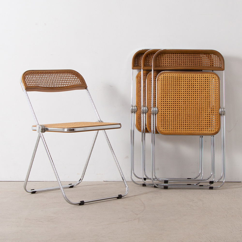 Plia Chair by Giancarlo Piretti for ANONIMA CASTELLI in Steel and Rattan
Italy , 1970s
イタリア人デザイナー、Giancarlo Piretti（ジャンカルロ・ピレッティ）によって、1967年にデザインされた Plia Chai（プリアチェア）。
経年変化したヴィンテージならではの、ラタンの風合いと、機能的なフォルムの印象的な一脚です。
座面の左右のパーツのみで折りたためる、現在の折りたたみ椅子のモデルとなった構造が特徴です。機能的で透明感のある美しいこの椅子は、発売以来、全世界で700万脚以上販売され、MoMAに収蔵されている他、数々の賞を受賞しています。
折りたたむと5cmのスペースに収まるスリムな設計。立ち上げた状態でもスタッキングが可能。
座面と背もたれは、ブナ材のフレームにカゴメ編みにしたラタン(藤)が張られています。ラタンの適度なしなりと天然素材ならではの質感が快適な座り心地を実現しています。

