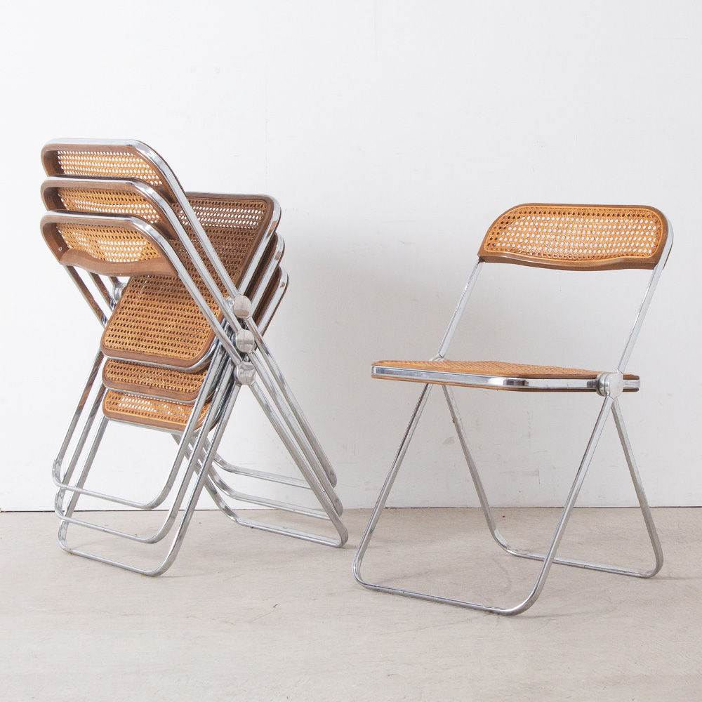 Plia Chair by Giancarlo Piretti for ANONIMA CASTELLI in Steel and Rattan
Italy , 1970s
イタリア人デザイナー、Giancarlo Piretti（ジャンカルロ・ピレッティ）によって、1967年にデザインされた Plia Chai（プリアチェア）。
経年変化したヴィンテージならではの、ラタンの風合いと、機能的なフォルムの印象的な一脚です。
座面の左右のパーツのみで折りたためる、現在の折りたたみ椅子のモデルとなった構造が特徴です。機能的で透明感のある美しいこの椅子は、発売以来、全世界で700万脚以上販売され、MoMAに収蔵されている他、数々の賞を受賞しています。
折りたたむと5cmのスペースに収まるスリムな設計。立ち上げた状態でもスタッキングが可能。
座面と背もたれは、ブナ材のフレームにカゴメ編みにしたラタン(藤)が張られています。ラタンの適度なしなりと天然素材ならではの質感が快適な座り心地を実現しています。
