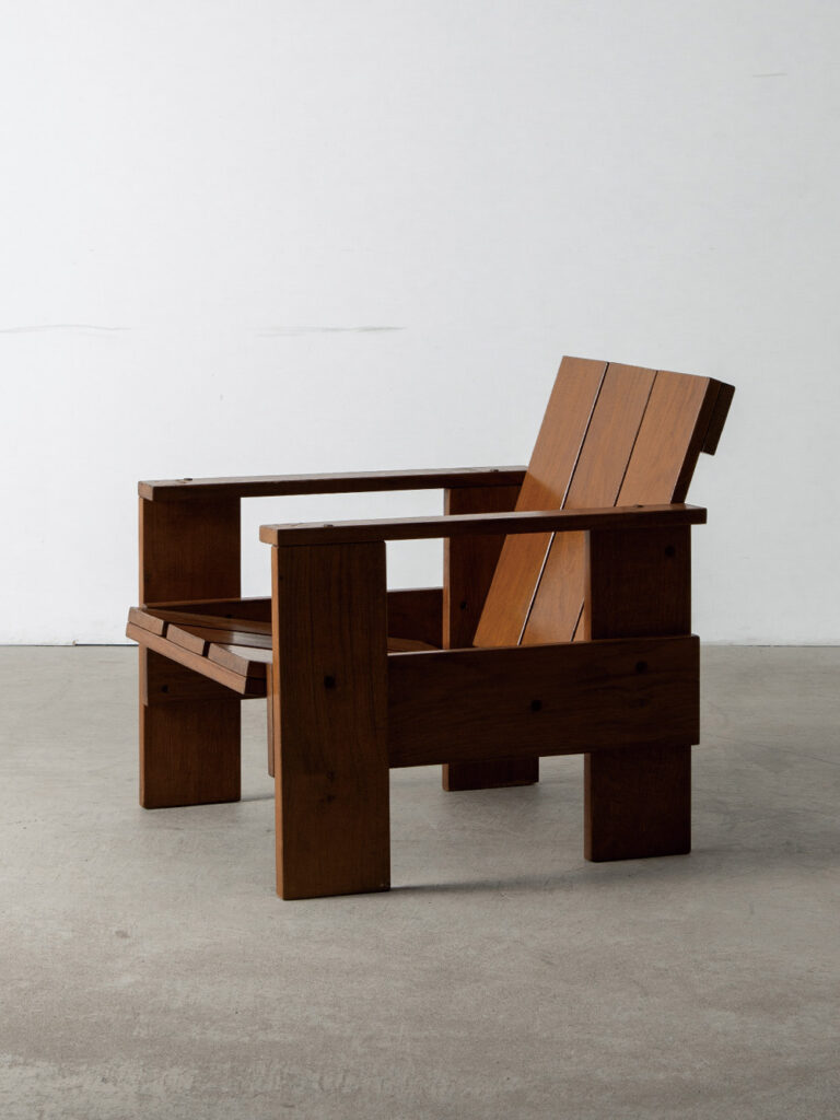 ‘Crate’ Lounge Chair by Gerrit Thomas Rietveld in Pine
Netherlands , 1960s
オランダ人デザイナー・建築家の Gerrit Thomas Rietveld (ヘーリット・トーマス・リートフェルト)によって1934年にデザインされた ‘Crate’ チェア。家具輸送に使われる木箱(Crate)から着想を得て生まれたシリーズ「Crate Furniture」のひとつ。
木箱に多用されるパイン材を使用し、真鍮ビスで組み立てるシンプルな構造が特徴で、購入者自身が一から組み立てを行うDIYキットとして販売されました。その合理的で質素な佇まいは、一部の評論家から「クラフトの腐敗」とも揶揄されましたが、リートフェルトは次のように応じています。
「上質な木材で丁寧に作られた家具は、傷や破損から守るために木箱に入れて出荷される。この木箱は、その高貴な家具よりも丈夫。さらに陽気な色合いで、職人のしかめっ面を感じさせない。だからこそ、最終的に ‘家具’よりも‘木箱’を選んだ人がいたはずだ」
1970年代に Cassina社によって復刻されますが、こちらの個体はそれ以前のミッドセンチュリー期に製造されたと推測されます。