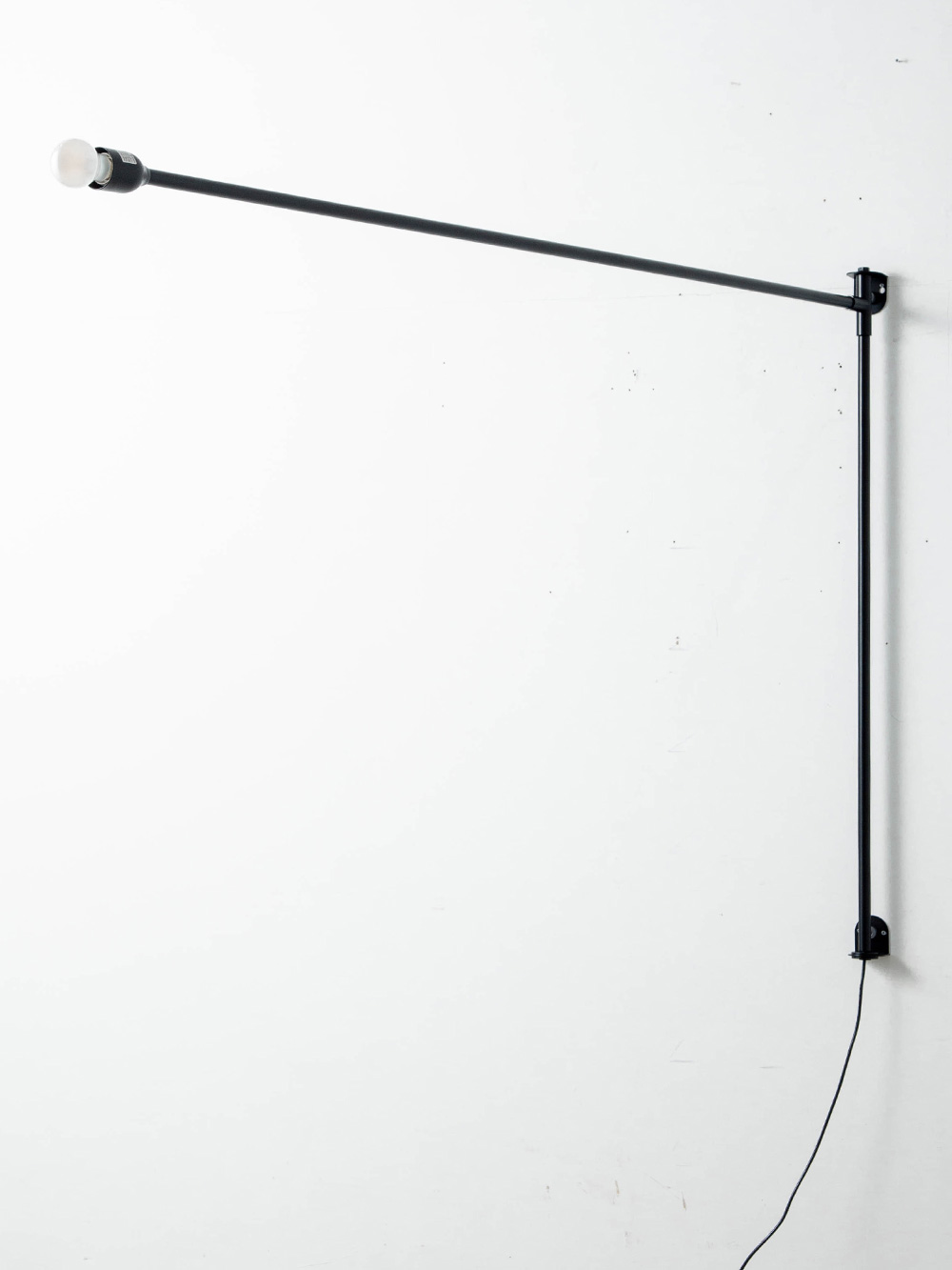 Potence Pivotante Wall Lamp by Charlotte Perriand for NEMO
Italy , 1930s
1938年にシャルロット・ペリアンによってデザインされた Potence Pivotante（ポテンス・ピヴォタンテ）ウォールランプ。
ヨットのブーム（帆を張る横木）から着想を得ており、扱いやすい回転式ランプとして設計されています。
スイッチから電球まで電線を導くために黒いチューブ状のパーツを2本使い、壁に固定されたアームは水平方向にほぼ180°回転します。
