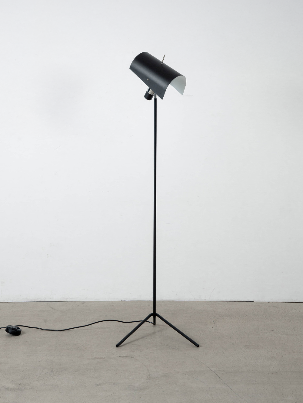 Claritas Floor Lamp by Vico Magistretti for NEMO
Italy , 1940s
1946年、ヴィコ・マジストレッティは自身初の照明デザインとなる Claritas（クラリタス）を Mario Tedeschi（マリオ・テデスキ）と共同で発表しました。
戦後の復興と軍需産業の転換という時代背景の中で、マジストレッティは初めて金属パイプの曲げ加工と、反射板としてのアルミ板を採用しました。
角度調節を可能にすることで、スポットライトとしても間接照明としても使用でき、理想的な照明効果を実現しています。
