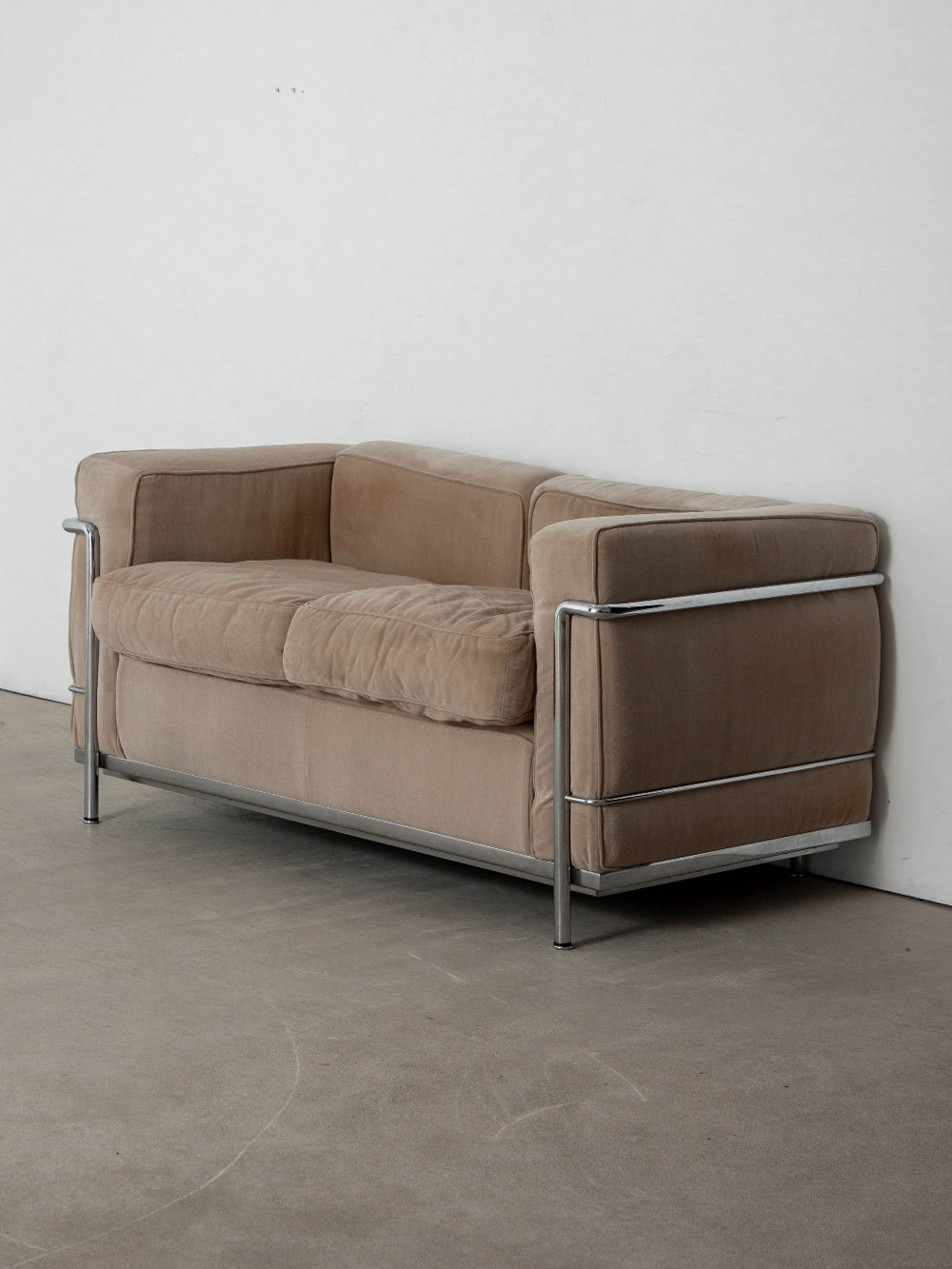 LC2 Sofa by Le Corbusier , Charlotte Perriand , Pierre Jeanneret for Cassina in Fabric and Chrome
France , 1980s
20世紀を代表する建築家・デザイナーの Le Corbusier（ル・コルビジェ）と、Charlotte Perriand（シャルロット・ペリアン）、Pierre Jeanneret（ピエール・ジャンヌレ）によって、1928年にデザインされた Fauteuil Grand Confort（フォトゥイユ・グラン・コンフォール）通称 LC2 ソファ。
1928年にフランスのヴィル＝ダヴレーにある、アメリカ人作家アンリ・チャーチの別荘のために制作され、1929年にパリのサロン・ドートンヌで開催された L'Équipement de l'Habitation（レキプマン・ドゥ・ラビタシオン）で初公開されました。
金属フレームとクッションが完全に独立した構造は、当時としては画期的な合理主義デザインとなりました。
余計な装飾を必要としない、機能そのものを美へと昇華したその佇まいは、新たな価値観を生み出し、時代を超えて受け継がれています。
こちらの個体はイタリア Cassina（カッシーナ）社製となり、フレーム裏面には当時の刻印と製造番号が刻まれています。
