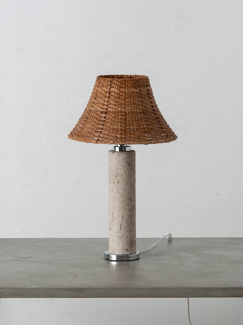 Table Lamp by Emanuele Scarnicci in Rattan , Travertine and Chrome
Italy , 1970s
イタリアの彫刻家・照明デザイナーである Emanuele Scarnicci（エマヌエーレ・スカルニッチ）によって、自身の工房でデザインされたテーブルランプ。
トラヴァーチンの円柱とクロームのベース、ラタンのシェードとのコントラストが生み出す、彫刻的な佇まいが美しい作品です。
ソケット下に当時のラベルが貼付されています。
