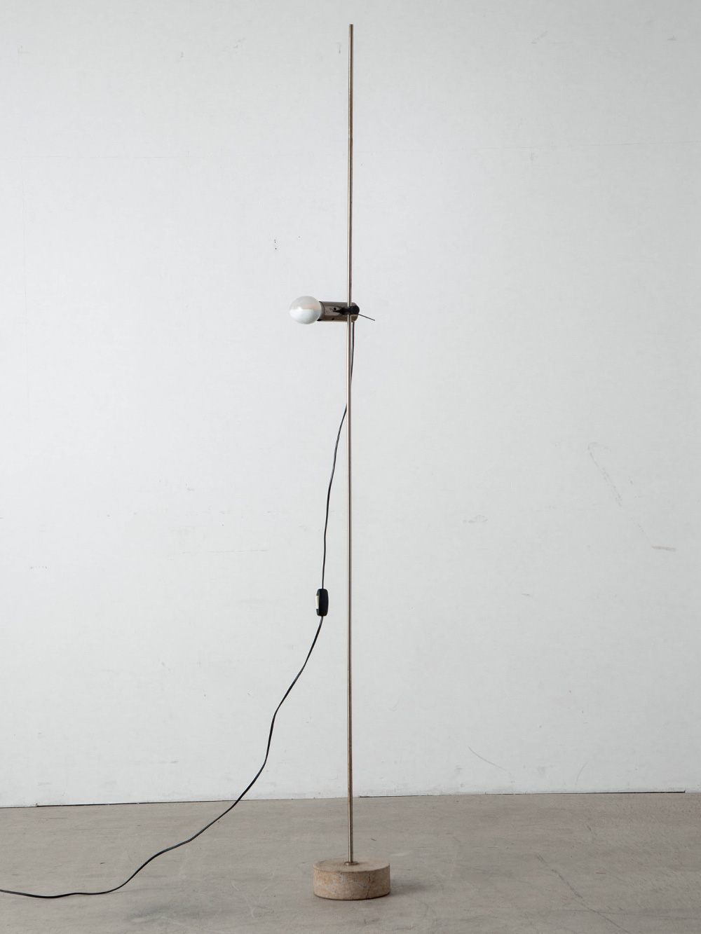 Agnoli 387 Floor Lamp by Tito Agnoli for Oluce in Chrome and Travertine
Italy , 1950s
イタリアのデザイナー Tito Agnoli（ティト・アニョーリ）によって、同国の Oluce（オルーチェ）社のために1954年にデザインされた Agnoli 387 フロアランプ。
家具や照明デザインにおける革新的かつミニマルなアプローチで知られ、当時の照明において不可欠とされていたシェードを排し、スライド式の光源そのものをデザインの主役とする無駄のない機能美を実現しました。
ミニマリズムの先駆けとなるデザインとして、Oluce社を代表するプロダクトの一つです。
