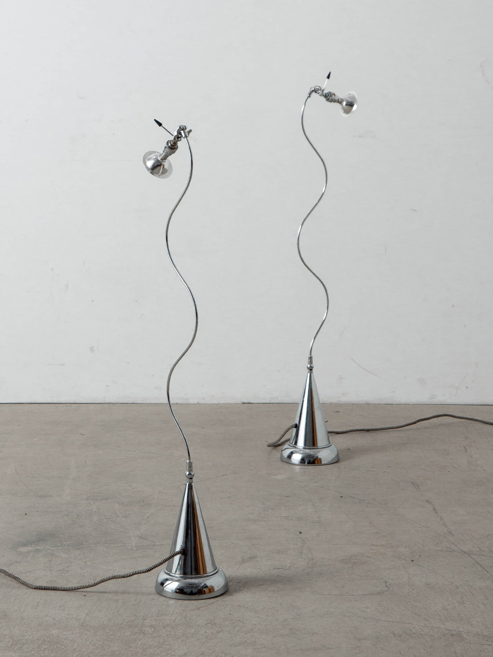 Floor Lamp by Andrea Bastianello for Disegnoluce in Chrome
Italy , 1980s
イタリアのデザイナー Andrea Bastianello（アンドレア・バスティアネッロ）によって、自身が創設した Disegnoluce（ディゼーニョルーチェ）社のためにデザインされたフロアランプ。
ボリューム感のある円錐形のベースと、有機的に波打つステムとのシルエットのコントラストが印象的で、同素材の構成によって生まれる調和が美しい照明です。
