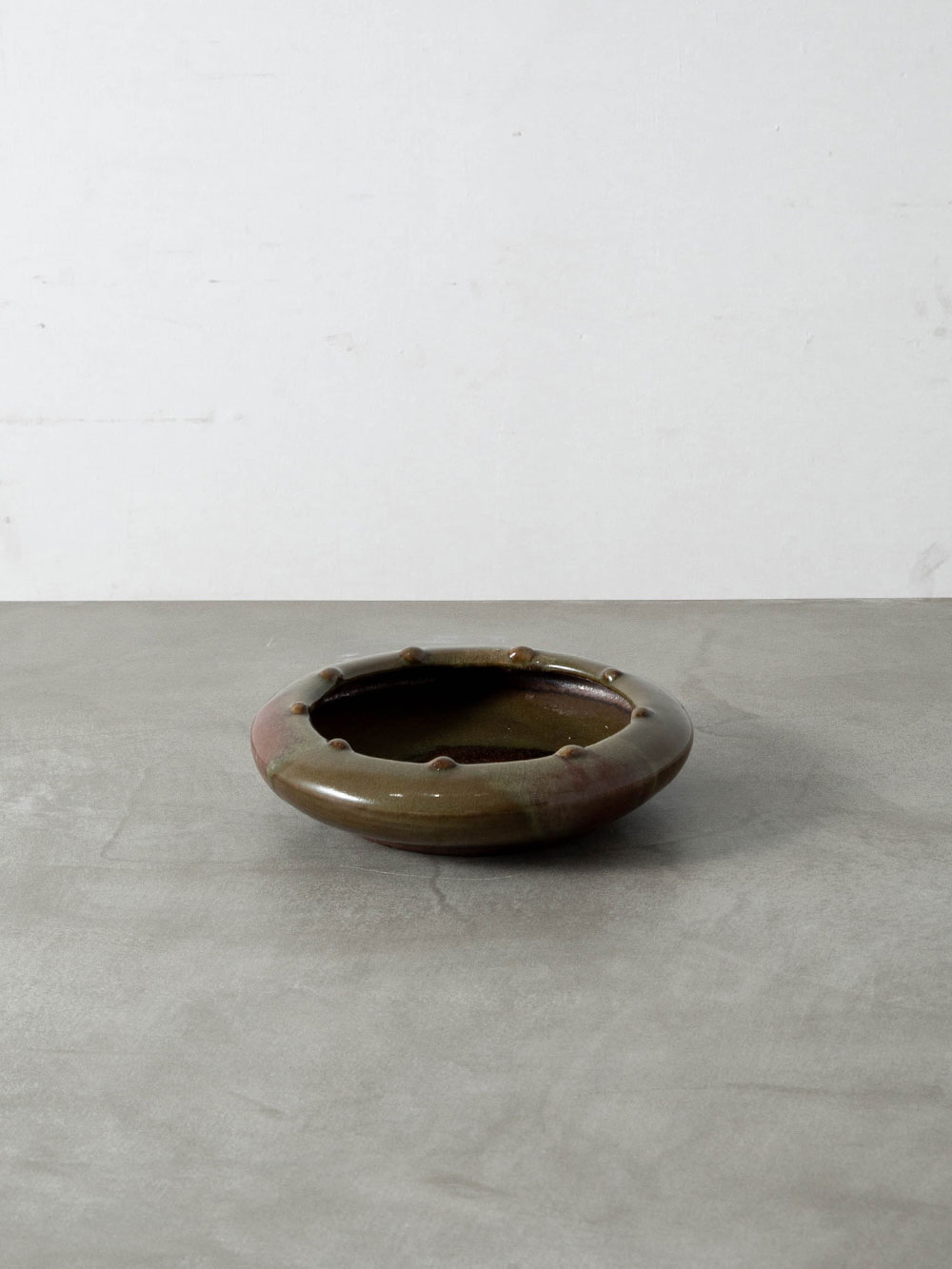 Serving Plate in Ceramic
America , 1970s
アメリカより、オリーブグリーンと赤褐色の釉色が織りなす豊かな表情に、リムを巡る立体的な装飾が調和したサービングプレート。
