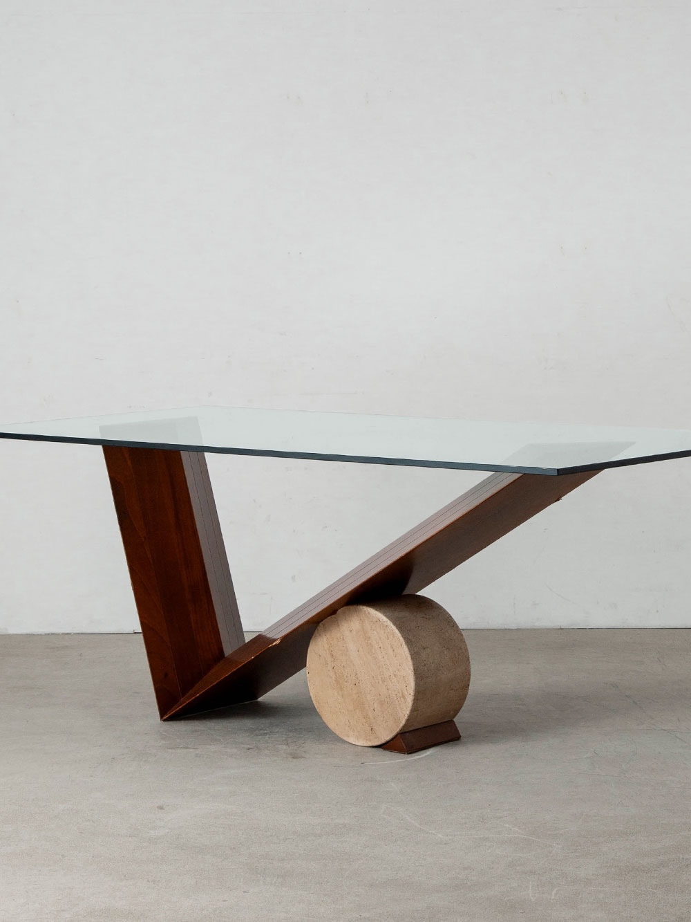 Valentino Table by Emanuele Zenere for Cattelan Italia in Glass , Wood and Travertine
Italy , 1990s
イタリアのデザイナー Emanuele Zenere（エマヌエーレ・ゼネーレ）によって、同国の Cattelan Italia（カッテラン・イタリア）社のために1991年にデザインされた Valentino（ヴァレンティーノ）テーブル。
V字型の木製フレームと円柱状のトラバーチンが互いに支え合うように構成されたベースに、厚みのあるガラス天板を組み合わせ、異素材の緊張感と均衡が際立つデザインに仕上げられています。
機能性と造形美を高い次元で融合させた、Cattelan Italiaを代表するダイニングテーブルのひとつです。
