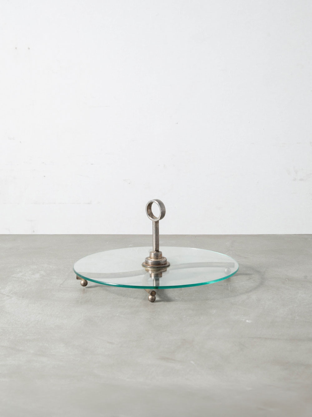 Serving Tray in Glass and Steel
Italy , 1960s
イタリアより、透明感のある円形のガラス天板と、有機的なアーチを描くスチールベースのコントラストが美しいサービングトレイ。
可動式のハンドルがアクセントとなり、テーブルウェアとしてはもちろん、ディスプレイトレイとしてもお使いいただけます。
