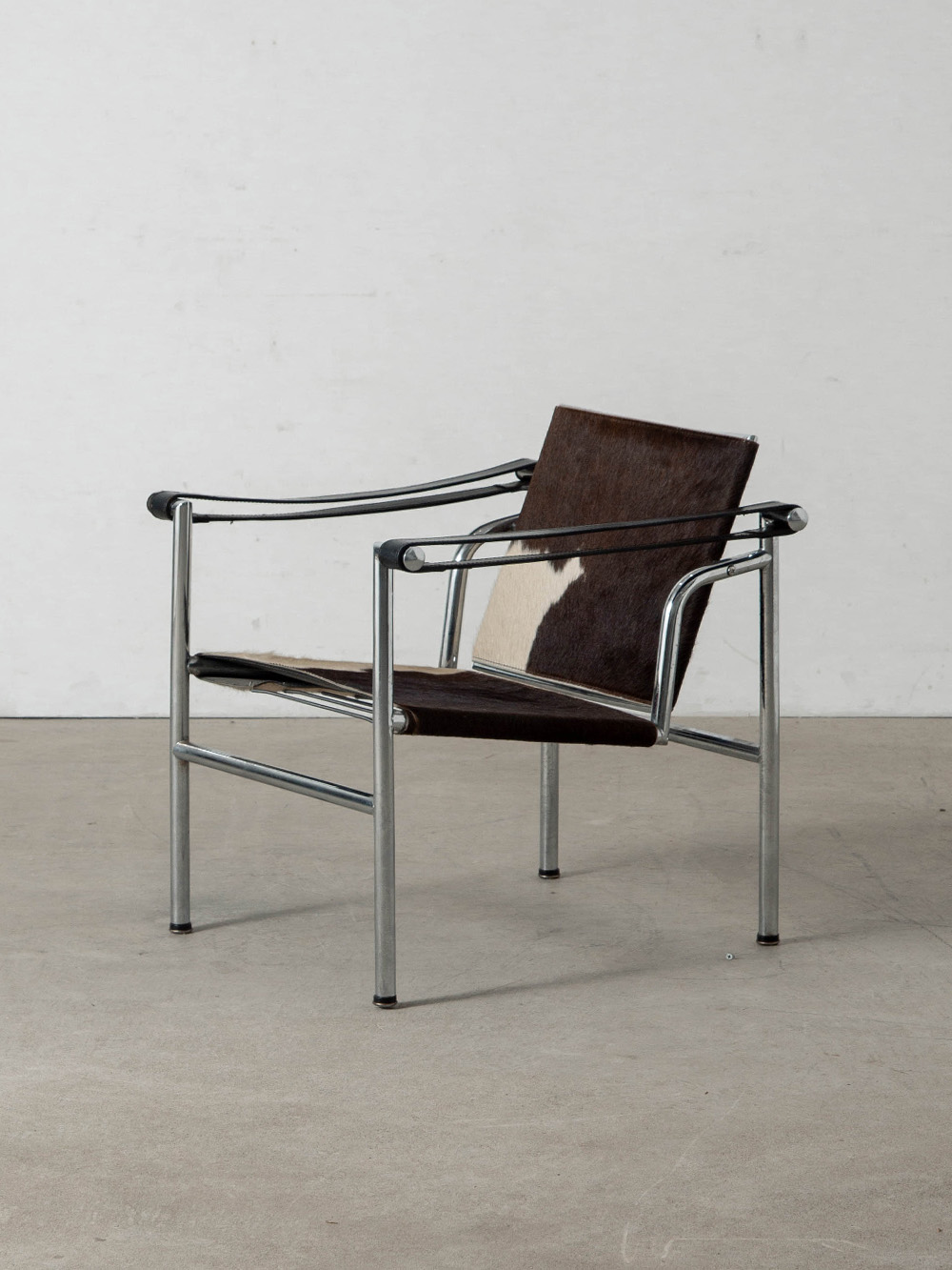 LC1 Chair by Le Corbusier , Charlotte Perriand , Pierre Jeanneret for Cassina in Calf Hair Leather and Chrome
France , 1970s
20世紀を代表する建築家・デザイナーの Le Corbusier（ル・コルビュジエ）と、Charlotte Perriand（シャルロット・ペリアン）、Pierre Jeanneret（ピエール・ジャンヌレ）によって、1928年にデザインされた Fauteuil à dossier basculant（フォトゥイユ・ア・ドシエ・バスキュラン）通称 LC1 ラウンジチェア。
1928年にフランスのヴィル＝ダヴレーにある、アメリカ人作家アンリ・チャーチの別荘のために制作され、1929年にパリのサロン・ドートンヌで開催された L'Équipement de l'Habitation（レキプマン・ドゥ・ラビタシオン）で初公開されました。
クローム仕上げのスチールパイプと革によって構成されたデザインは、可動式の背もたれが身体の動きに追従する合理的な構造を備えています。
余計な装飾を必要としない、機能そのものを美へと昇華したその佇まいは、新たな価値観を生み出し、時代を超えて受け継がれています。
こちらの個体はイタリア Cassina（カッシーナ）社製となり、フレーム裏面には当時のラベルが貼られています。
