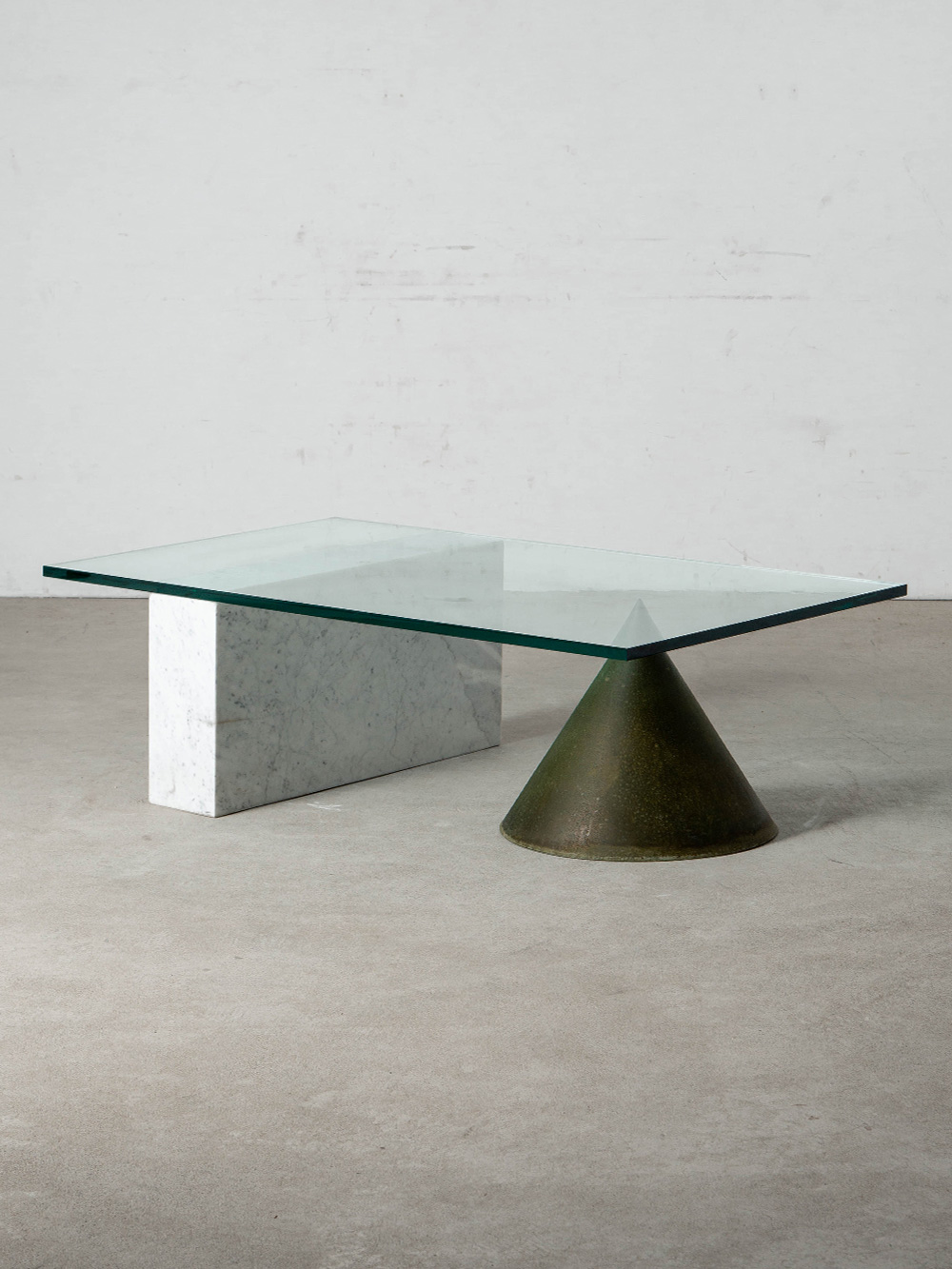 Kono Coffee Table by Lella and Massimo Vignelli for Casigliani in Marble , Copper and Glass
Italy , 1980s
イタリア人デザイナー Lella and Massimo Vignelli（レッラ＆マッシモ・ヴィネッリ）によって、同国の Casigliani（カシリアーニ）社のために1984年にデザインされた Kono（コーノ）コーヒーテーブル。
グリーンに酸化させた銅の円錐形とマーブルのブロックベースがガラス天板を支える、幾何学的な造形が美しいテーブルです。
