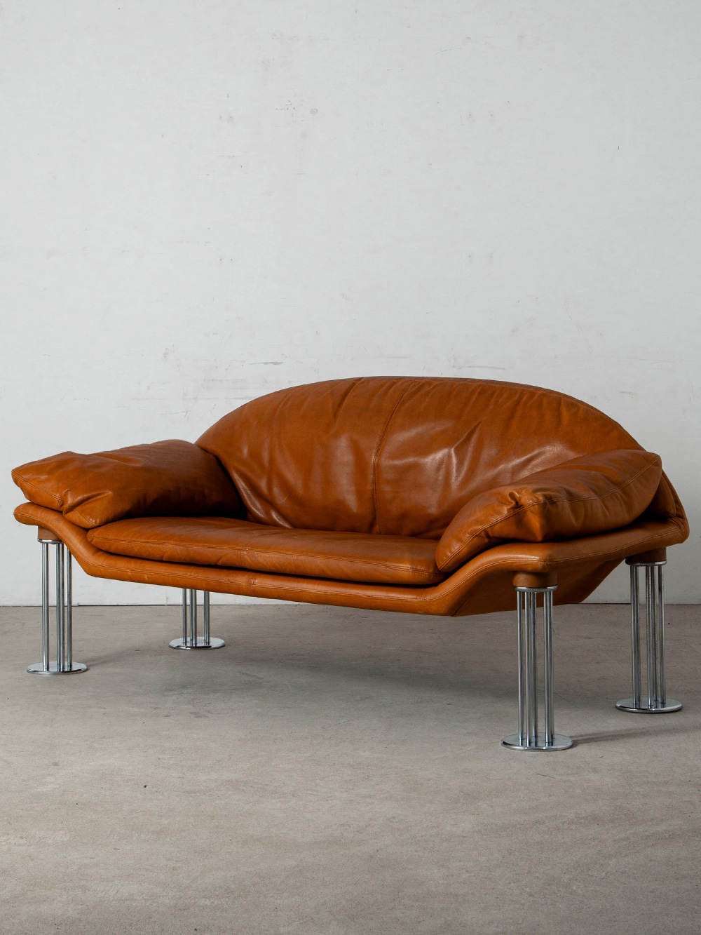 Air Sofa by Burkhard Vogtherr for Hain & Thome in Leather and Chrome
Germany , 1980s
ドイツのデザイナー Burkhard Vogtherr（ブルクハルト・フォークテア）によって、Hain & Thome（ハイン&トーメ）社のためにデザインされた Airソファ。
ボリュームのあるレザーのシートをクロームフレームで支え、モデル名の通り、複数の細い脚部によって本体が浮遊するような印象の軽やかな構造が特徴です。
