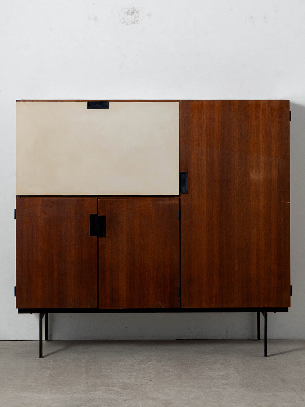 CU01 Cabinet By Cees Braakman for Pastoe in Teak and Steel
Netherlands , 1950s
オランダのデザイナー Cees Braakman（ケース・ブラークマン）によって、Pastoe（パストー）社のために1958年にデザインされた 'CU01' キャビネット。
'U+N Series' として多彩なバリエーションで展開され、後に 'Japanese Series' とも称される代表的なモデルのひとつ。 日本の美学に着想を得たミニマルな構成が際立ち、シリーズを象徴するハンドルディテール、深みのあるチーク材、そして緻密に計算されたプロポーションとコンポジションが見事に調和しています。
パストー社のディレクター兼デザイナーを務めていたブラークマンの理念を明確に体現するデザインです。
